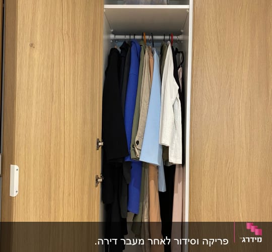 ארון בגדים עם בגדים תלויים ומדף עם שמיכה מקופלת